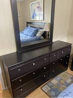 Full view of long dark wood dresser with attached mirror in bedroom setting.