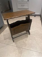 Front perspective showing the wooden tabletop and magazine storage compartment beneath.