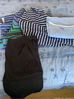Photo showing the three women's 3XL T-shirts stacked with a pair of black shorts on a bed with a floral-patterned sheet.