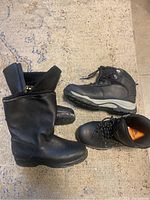 Photo showing three winter and hiking boots including a black winter boot with a high top and zip closure, and two hiking boots with hiking soles and lace-ups.