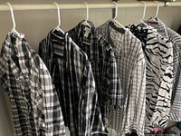Seven black and white women's dress shirts hanging on white hangers showing different patterns.