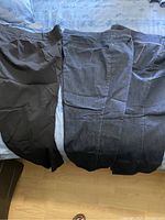 Black pants and three pairs of dark wash jeans laid out on bed.