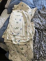 Floral cream colored pyjama set folded on bed showing pattern detail.