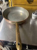 Top view showing the interior metal surface of the 10-inch copper sauté pan and attached brass handle with patina.