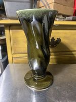 Front angled view of green and brown glazed Hull Pottery vase with twisted design on pedestal base