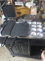 Photo showing all pans in the lot including pancake form pan, griddles, cake pans, and muffin pans.