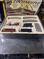 Full Feldstein Desktop Locomotive Train Set in box with plastic insert showing unassembled locomotive, coal tender, train cars, and metal curved and straight track pieces.