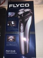 Front of the Flyco shaver box showing the model FS312US and features like intelligent system, body washable, and floating dual-track foil.