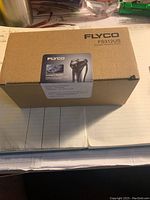 Cardboard outer packaging box labeled Flyco FS312US Hearing Aid Shaver opened for display.