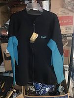 Full view of the black wetsuit top with blue sleeves hanging on a hanger showing the front zipper and Goldfin logo on the chest.
