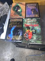 Four hardcover fantasy books by R.A. Salvatore laid out on a flat surface, showing front covers of Servant of the Shard, Passage to Dawn, Siege of Darkness, and The Dragon King.