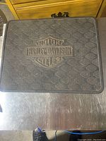 Full view of black Harley Davidson floor mat showing overall color, size and embossed logo pattern.
