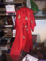 Full view of red men's kimono hanging, showing butterfly embroidery and belt.