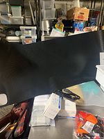 Black textured desk pad partially rolled out with various boxed small items and packaged socks on a metallic surface.