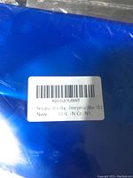 Close-up of folded blue collapsible emergency water container with label showing 10L capacity and 'Made in China'