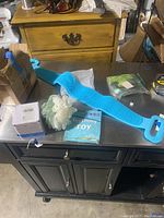 Overview of miscellaneous bath and baby items displayed on table including bath back scrubber, mesh scrubbie, teething toy package, gender reveal baseball, and wire coil.