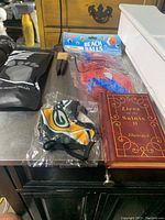 Overall lot contents on a table including Green Bay Packers mask, book, beach balls, railroad spikes and orthotic insoles