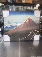 Full view of the 16x20 canvas print depicting Mount Fuji with rainstorm clouds and Japanese characters. Canvas has corner protectors.