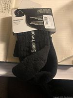 Pair of SmartWool Light Mini low cut socks in black, attached tag showing SmartWool branding and product details.