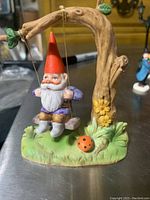 Front view of gnome on swing hanging from tree details including facial features, colors, and base