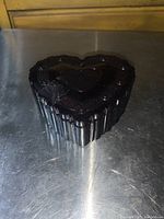 Top and side view of heart-shaped ruby red glass ring dish showing textured heart patterns and scalloped edges.