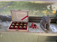 Photo showing the Spiegel brass napkin rings in original box, the small firefighter, dog, and car figurines, and the Lenox elephant figurine grouped together on a windowsill.
