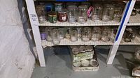 Shelf with assortment of clear glass jars, mostly embossed, some with lids and some without.