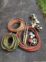 Overview of entire welding lot on asphalt, showing coiled hoses, torches, and gauges.