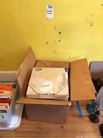 Cardboard box with plates wrapped in original vintage packaging marked 'Annie'.