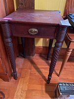 Front view of a wooden side table with a drawer, showing the drawer pull and spiral legs.
