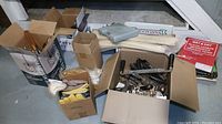 Full view of the lot showing boxes containing assorted tools, abrasives, and leather gloves