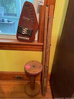 Full view of the vintage Oscar Schmidt Autoharp, wooden spool, and two yardsticks standing vertically.
