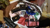 Photo of various bags, purses, wallets and belts arranged on a table, showing different styles, colors and materials