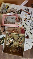 Photo showing full assortment of costume jewellery laid out on table including bracelets, necklaces, earrings, rings, and pins, some in trays