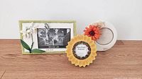 Three floral picture frames placed on a wooden surface against a white background.
