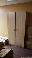 Full view of the Ikea wooden closet cabinet with two vertical doors, three drawers at the bottom right, and two handles on the doors.