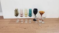 Front view showing all stem glasses including colored flutes, black goblet, amber martini glass, and clear wine glasses.