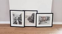 Three framed black and white photos of Venice against a white wall and wooden floor, showing they need resetting in frames