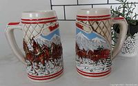 Two ceramic Budweiser 1995 steins with embossed detailed Clydesdale horse scenes and winter backgrounds shown from front and side angles.