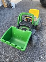 Front view of green and yellow John Deere mini loader with large green front bucket and yellow seat