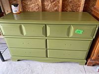 Full front view of the green wooden dresser with six drawers and no hardware. Can of paint on top of the dresser.