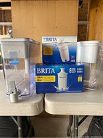 Two Brita water pitchers and two boxes of Brita filter cartridges (3-pack and 8-pack) displayed on a table.