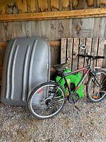Photo showing mountain bike leaning against car roof top carrier next to wooden pallet and pool float.