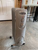 Gray Noma oil filled heater photographed standing upright showing front controls and casters.