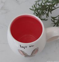 Top angle of the mug highlighting the red interior and part of the exterior design with the phrase ‘hop on’.