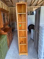 Tall narrow wooden corner shelf with five shelves, light wood finish, visible wear and wood damage on bottom shelf