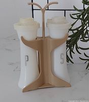 Front view of the Tupperware Hourglass salt and pepper shaker set with stand displaying the 'S' and 'P' embossing clearly, showing condition and design.