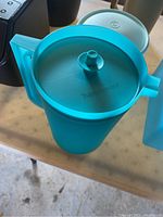Blue Tupperware pitcher with lid and handle shown on table.