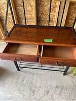 Photo showing two wooden drawers open with metal handles and a wooden top shelf supported by a black metal frame.