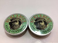 Top view of two sealed tins of Burt's Bees Res-Q Ointment 0.6 oz showing label and design.